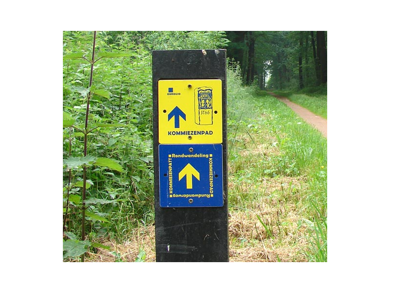 Blue and yellow signposting in the forest for the Komiezenpad trail.