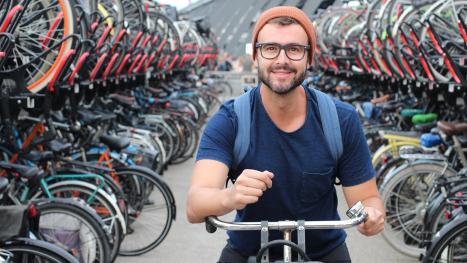 View of a large bike parking area with a young man about to ride away.