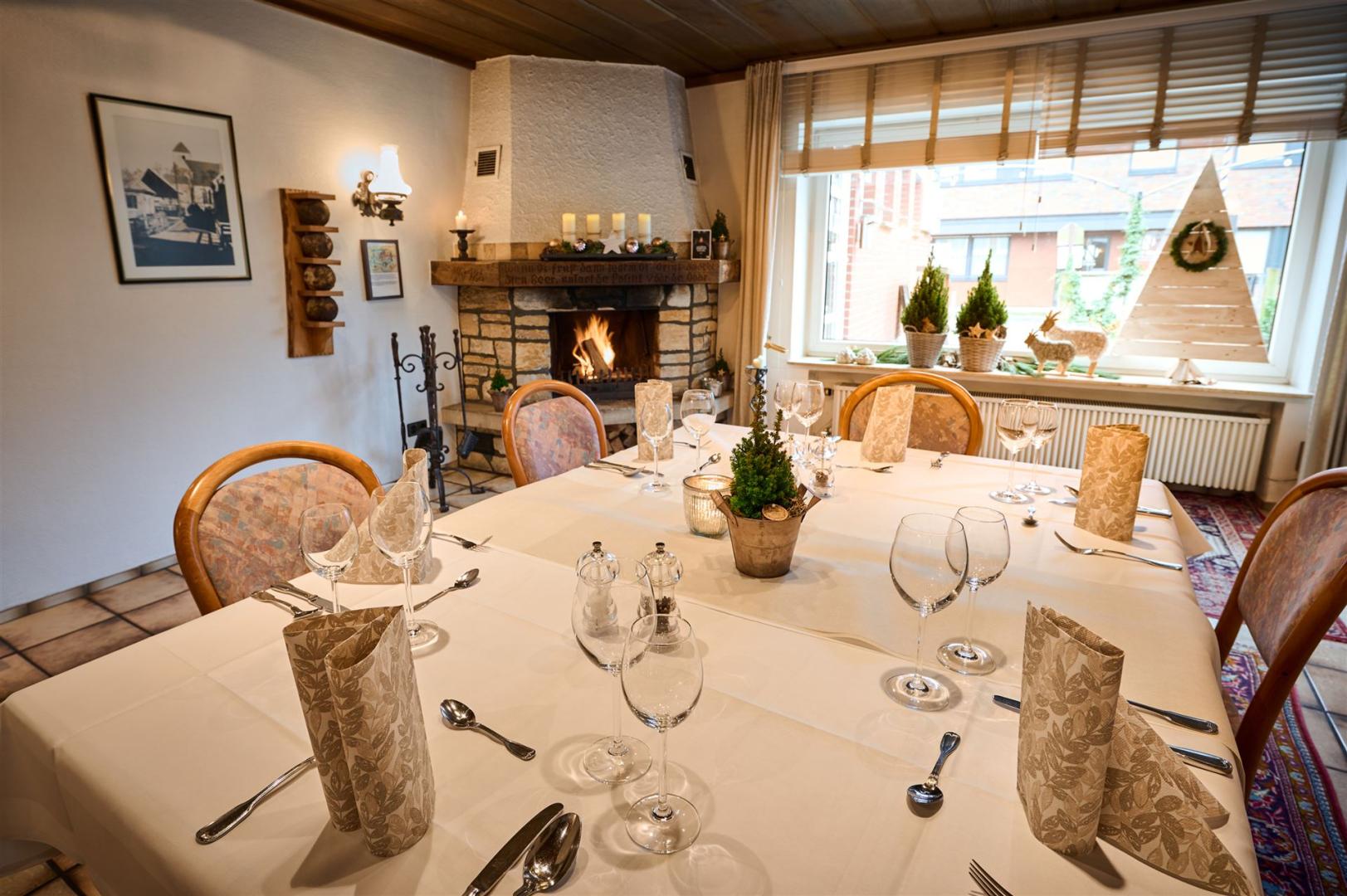 Photo of the club room with a set table and a burning fireplace.