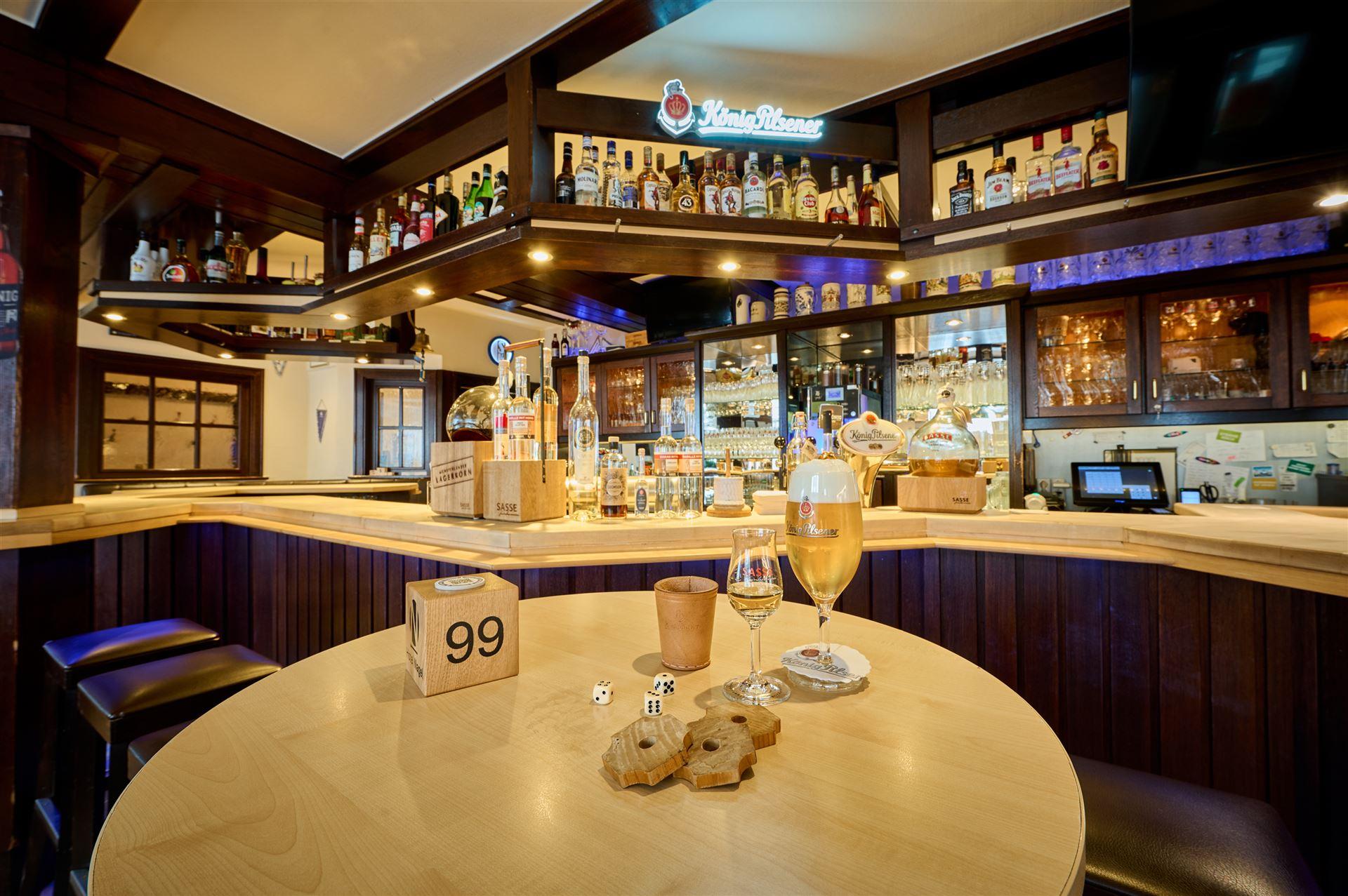 Close-up of the bar counter with a glass of König Pilsener and a liqueur from Distillery Sasse.