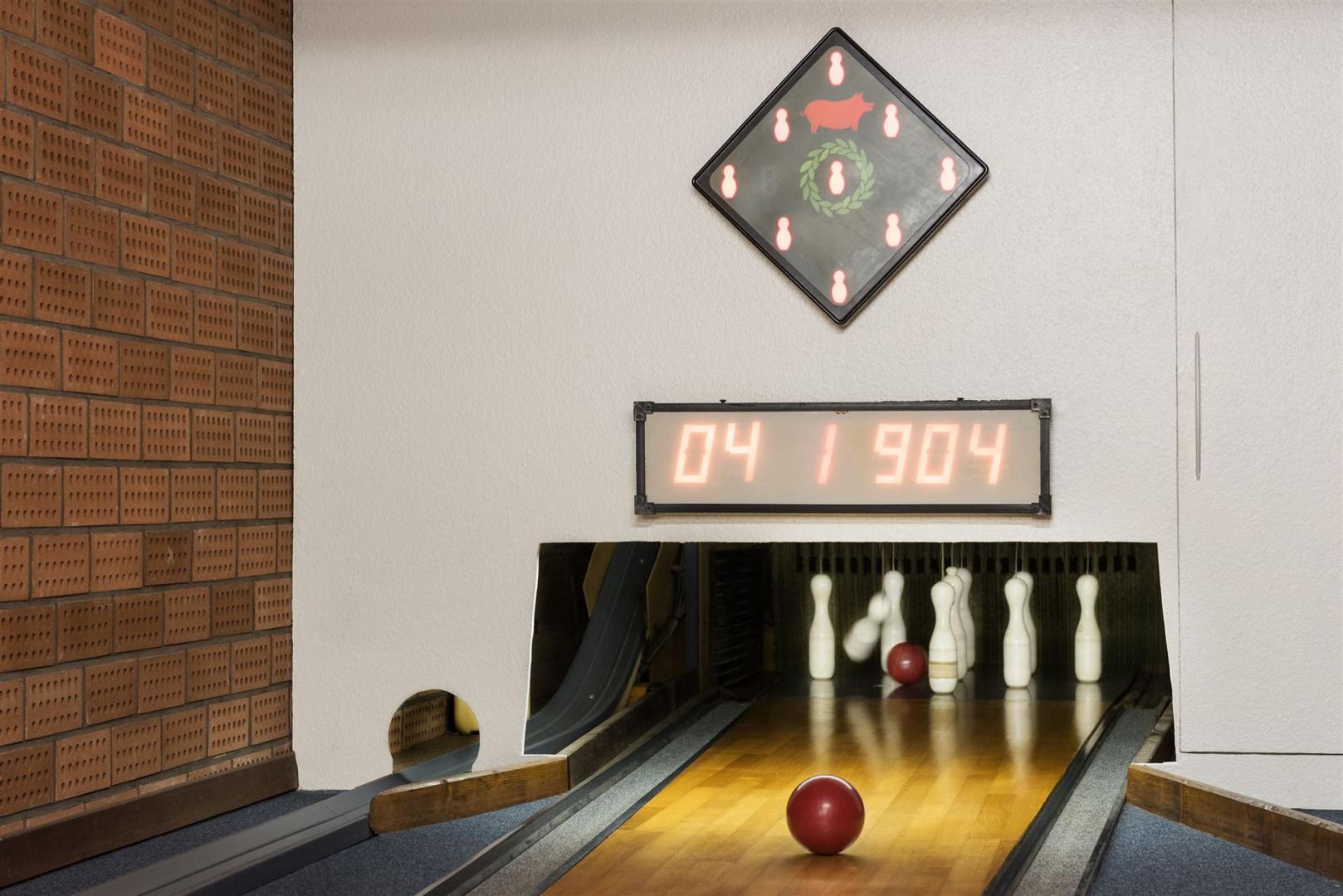 The image shows the end of the bowling alley with pins and a scoreboard.