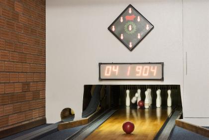The image shows the end of the bowling alley with pins and a scoreboard.
